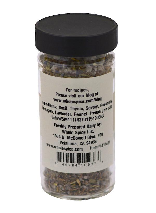 A glass jar with a black lid contains Whole Spice Inc. Herbes de Provence Sea Salt, featuring basil, thyme, rosemary, tarragon, fennel, and lavender on the label along with a barcode and company contact information.
