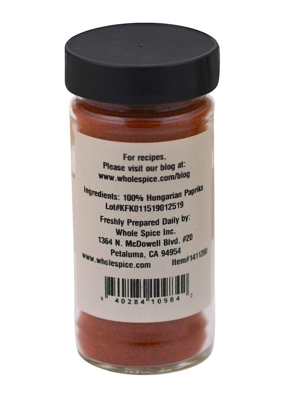 A clear spice jar with a black lid holds vibrant red Whole Spice Inc. Hungarian Paprika—ideal for goulash. The label lists 100% Hungarian paprika as the ingredient, along with manufacturer and contact details.