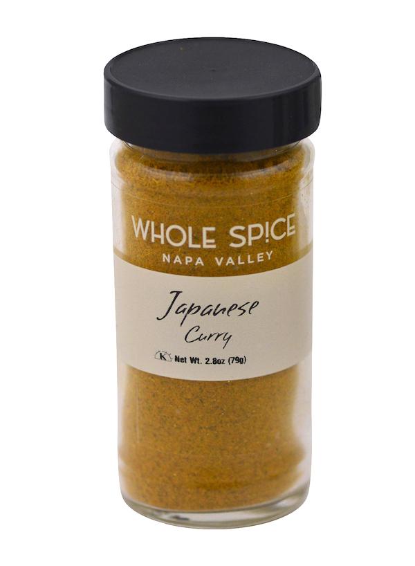 A clear glass jar with a black lid holds yellow Japanese Curry powder by Whole Spice Inc.—ideal for authentic Japanese or coconut curry. The label reads Japanese Curry, Net Wt. 2.8oz (79g).