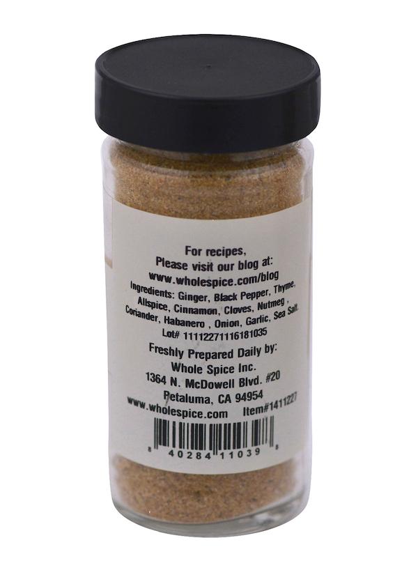 A clear jar of Whole Spice Inc. Jerk Seasoning with a black lid features a back label listing ingredients like ginger, black pepper, and thyme—ideal for making aromatic spice rubs or classic Jerk dishes.