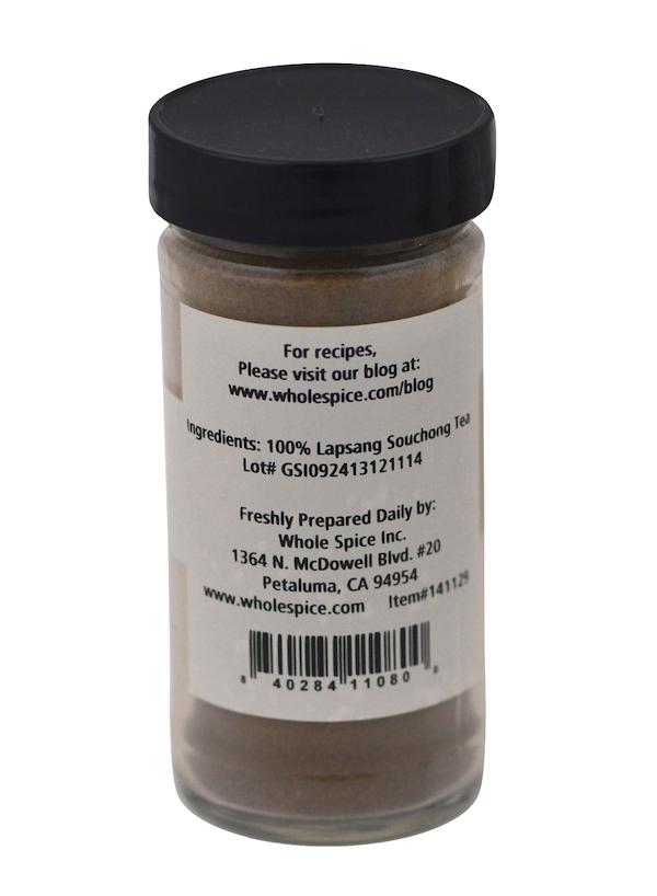 A clear spice jar with a gray lid labeled "Lapsang Souchong Tea Powder" by Whole Spice Inc., known for its smoky flavor and pine aroma. The label lists the website, address, barcode, and additional product details.