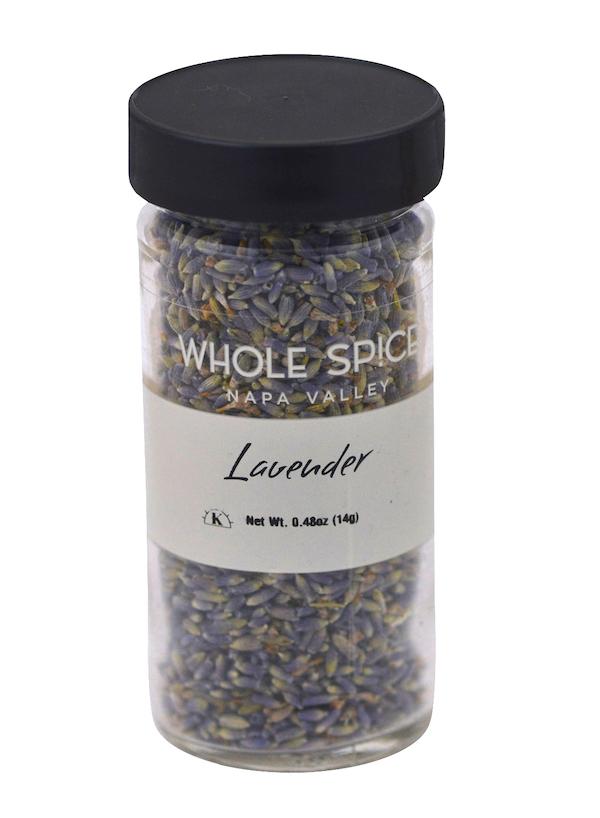 A clear spice jar with a black lid from Whole Spice Inc., labeled Lavender, contains dried lavender flowers for culinary use and weighs 0.48 oz (14g).