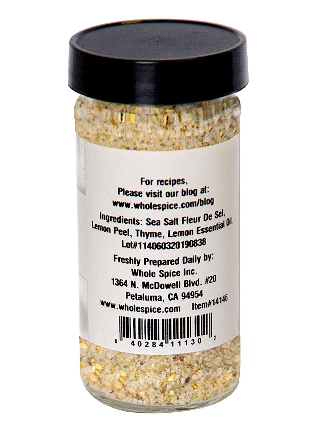 Lemon Thyme Sea Salt by Whole Spice Inc. comes in a glass jar with a black lid and a label listing French Sea Salt, Fleur de Sel, lemon peel, thyme, and lemon essential oil. Company info is on the back, with a barcode at the bottom.