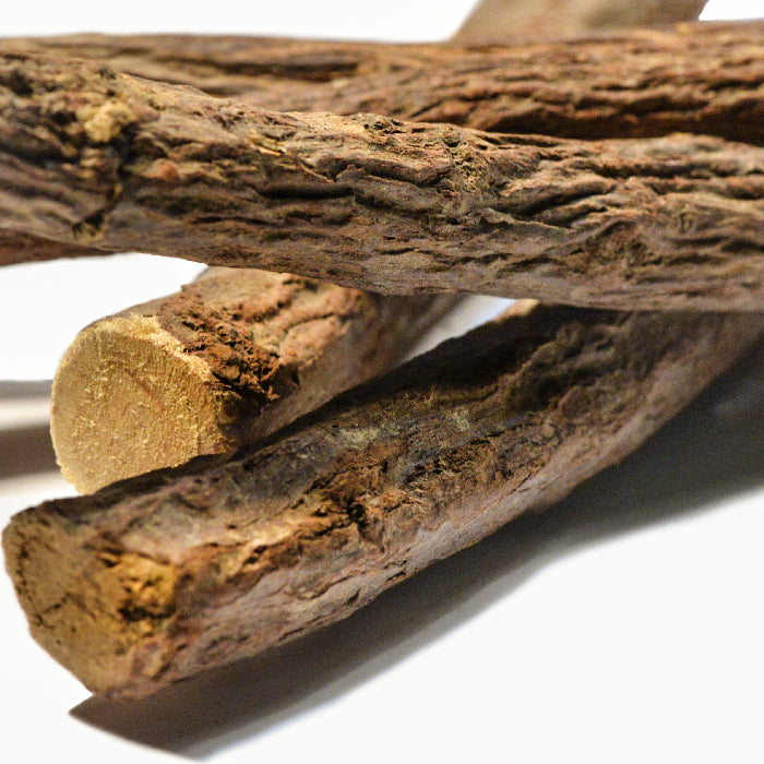Close-up of several Whole Spice Inc. Licorice Sticks 6 inch, stacked to display their natural, textured brown surface and fibrous ends against a white background.