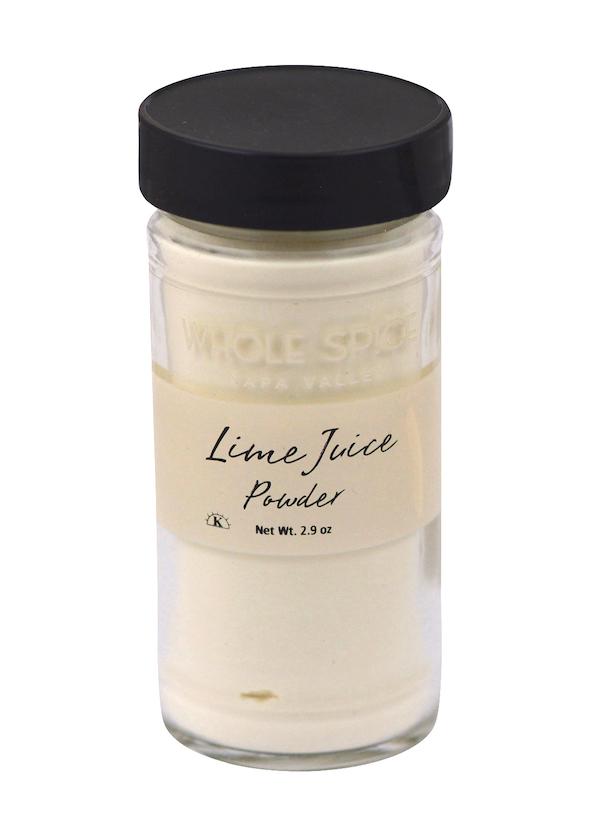 A clear glass jar with a black lid holds off-white Lime Juice Powder—a zesty lime juice substitute. The label reads “Lime Juice Powder, Net Wt. 2.9 oz” with the brand “Whole Spice Inc.” partially visible at the top.