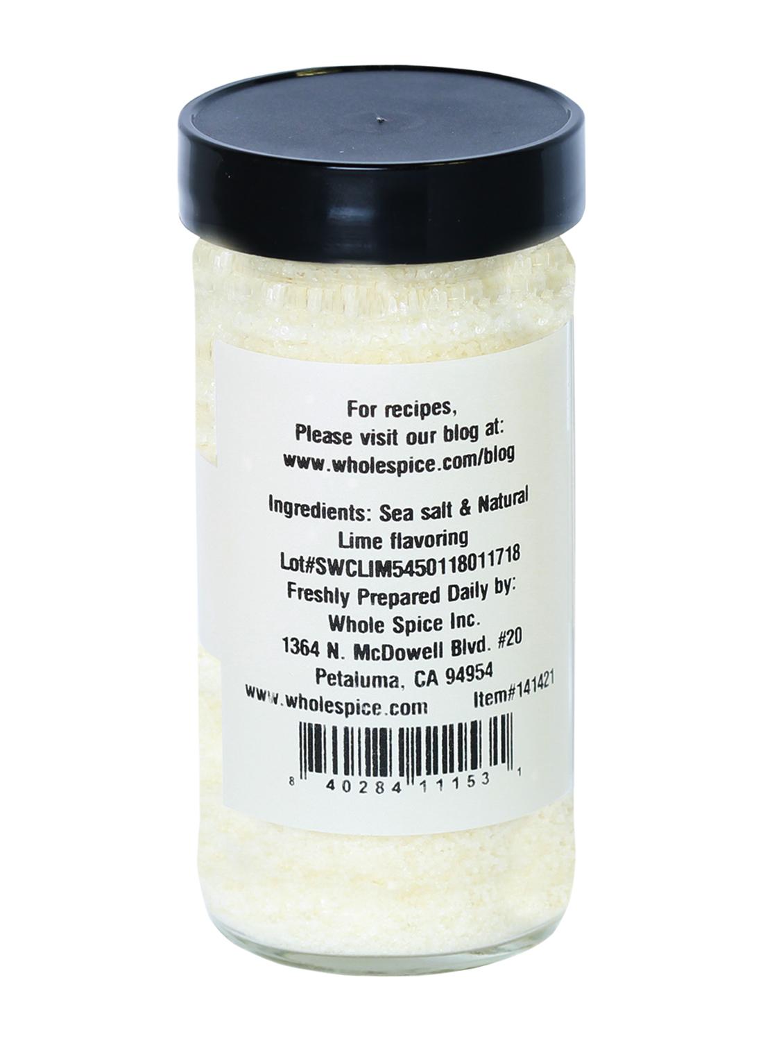 Whole Spice Inc. Lime Salt is coarse sea salt with natural lime powder in a clear jar with a black lid. The label lists ingredients, manufacturer info, and has a website for recipes. Enjoy its vibrant citrus flavor in your dishes!.