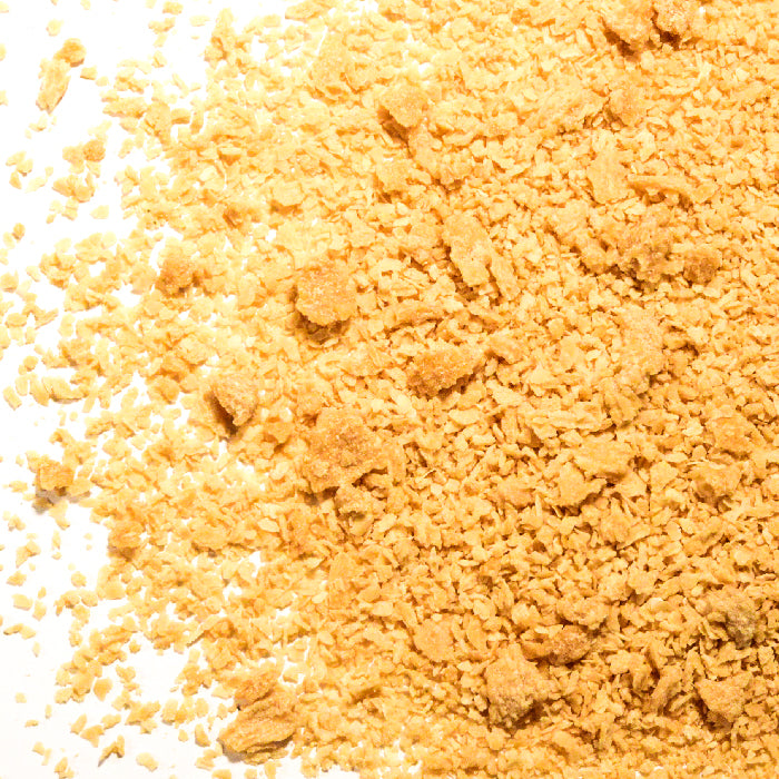 Golden-brown panko breadcrumbs scattered on a white surface feature fine and large flakes—ideal for adding crunch to holiday treats or enjoying with Whole Spice Inc.'s Maple Cranberry Sugar.