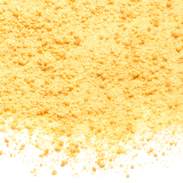 A close-up of Whole Spice Inc. Maple Sugar—a natural yellow powder sweetener—spreads across a white surface with fine particles scattered along the edge.