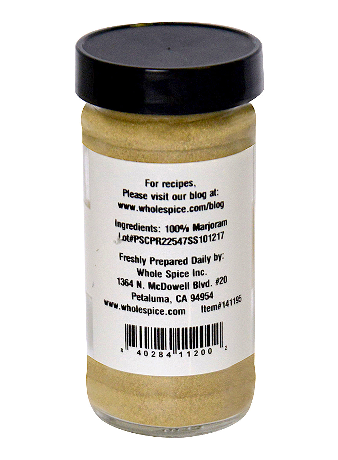A clear spice jar with a black lid contains pale yellow Marjoram Powder by Whole Spice Inc. The label lists 100% marjoram and provides company info, including an address in Petaluma, California.