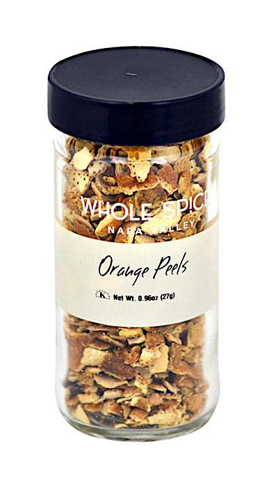 A clear glass jar with a black lid contains dried orange peels from Whole Spice Inc., adding vibrant citrus flavor to recipes. The label reads Orange Peels and displays a net weight of 0.96 oz (27g).
