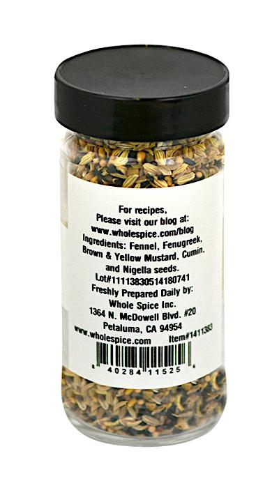 A clear spice jar with a black lid contains Panch Phoron (Bengal Five-Spice) by Whole Spice Inc.—a blend of fennel, fenugreek, brown & yellow mustard, cumin, and nigella seeds. The white label lists ingredients, company info, and roasted duck recipe tips.