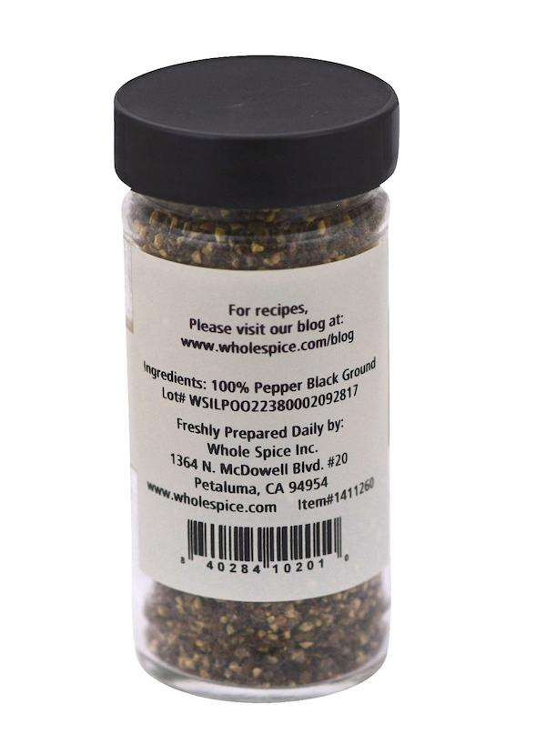 A clear spice jar with a black lid contains Whole Spice Inc.'s Pepper Black Coarse #3. The label lists 100% ground black pepper, company details, website, and a barcode. Known as the King of Spices.