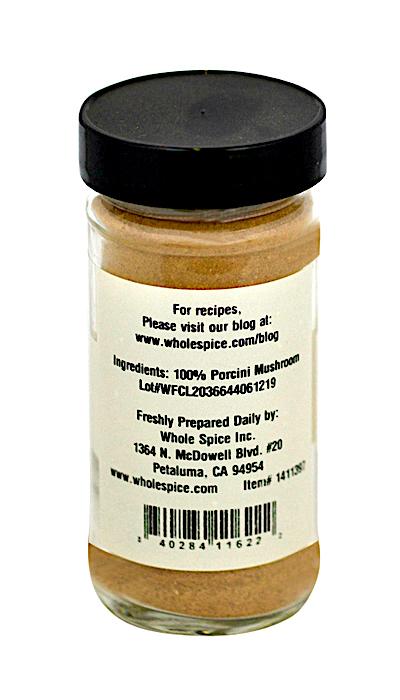 A clear spice jar with a black lid contains Porcini Mushroom Powder from Whole Spice Inc., labeled as 100% porcini mushroom, and displays the company info plus a barcode.