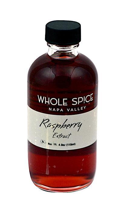 A clear glass bottle of Whole Spice Inc. Raspberry Extract with a black screw cap contains 4 oz (118 ml) of reddish liquid and features natural raspberry fruit flavoring on the label.