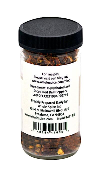 A clear plastic jar with a black lid contains Roasted Red Bell Pepper Diced from Whole Spice Inc. The white label lists ingredients, company info, and a barcode. Whole Spice Inc. is based in Petaluma, California.