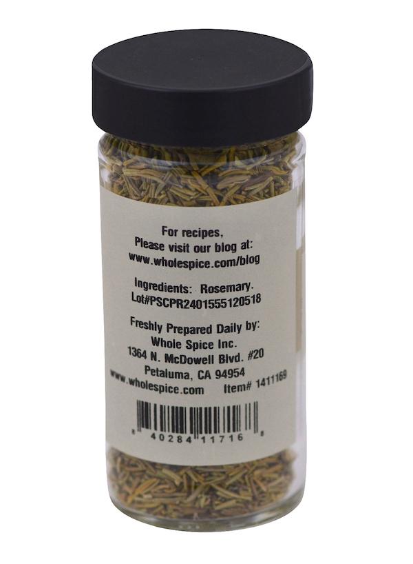 A clear glass jar with a black lid contains Whole Spice Inc. Rosemary. The label lists rosemary as the sole ingredient and includes preparation, company, and barcode information.