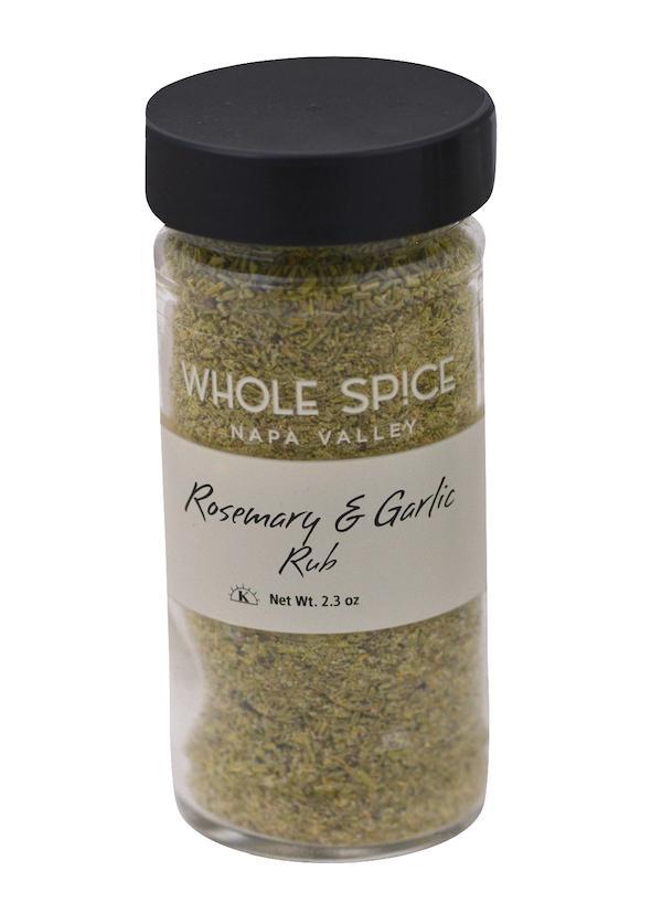 A clear spice jar with a black lid labeled Whole Spice Inc. Rosemary & Garlic Rub, Net Wt. 2.3 oz, filled with a greenish gourmet blend—ideal as a rosemary garlic herb rub to elevate your favorite meat seasoning.