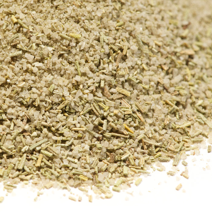 A close-up of dried Rosemary Salt by Whole Spice Inc., showcasing green and beige flakes—ideal for adding gourmet flavor to your dishes.