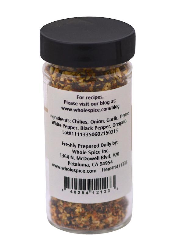 A clear spice jar with a black lid from Whole Spice Inc. displays a Salt-Free Turkey Brine Seasoning label listing chilies, onion, garlic, thyme, white pepper, black pepper & oregano—ideal for moist turkey. Company details are beneath the ingredients.