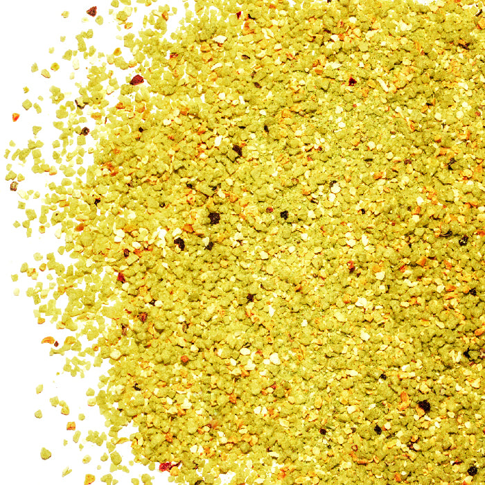 A close-up of Whole Spice Inc. Rosemary Lemon Salt shows yellow-green seasoned granules with larger chunks and flecks on a white background—perfect for adding a burst of flavor to your dishes.