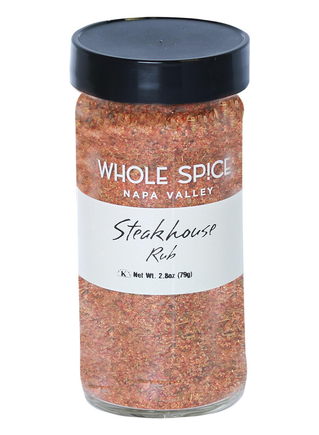 A clear glass jar with a black lid filled with Whole Spice Inc. Steak House Rub, a savory beef seasoning ideal for grilling, is labeled with the product name and a net weight of 2.8 ounces (79 grams).