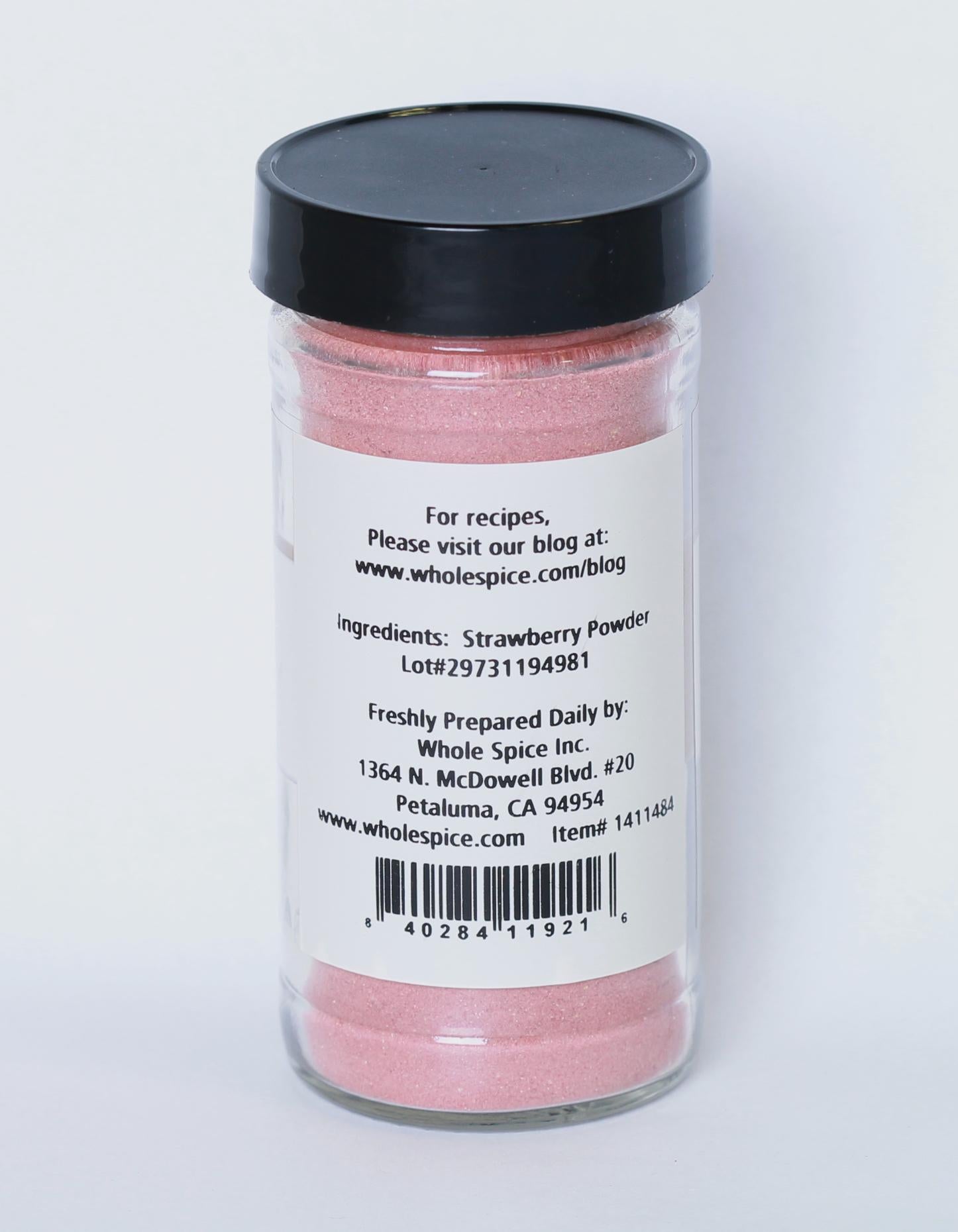 A clear spice jar with a black lid holds Strawberry Fruit Powder by Whole Spice Inc., made from dehydrated strawberries. The label features the brand, website, barcode, lot number, and highlights natural energy as a key benefit.