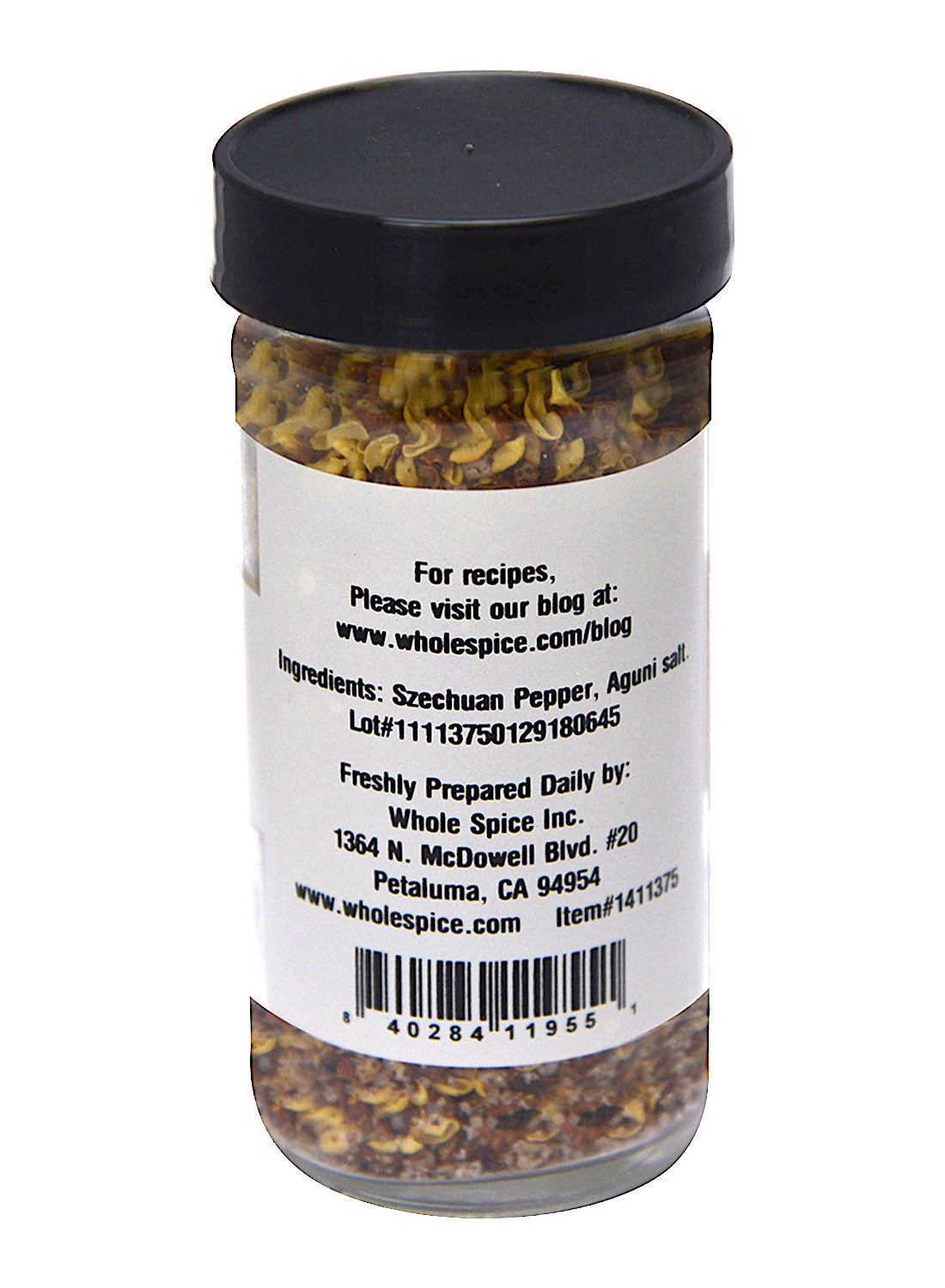 A clear spice jar with a black lid from Whole Spice Inc. contains Szechuan Salt. Its label lists Szechuan pepper and French sea salt as ingredients, plus company contact details and a barcode at the bottom.