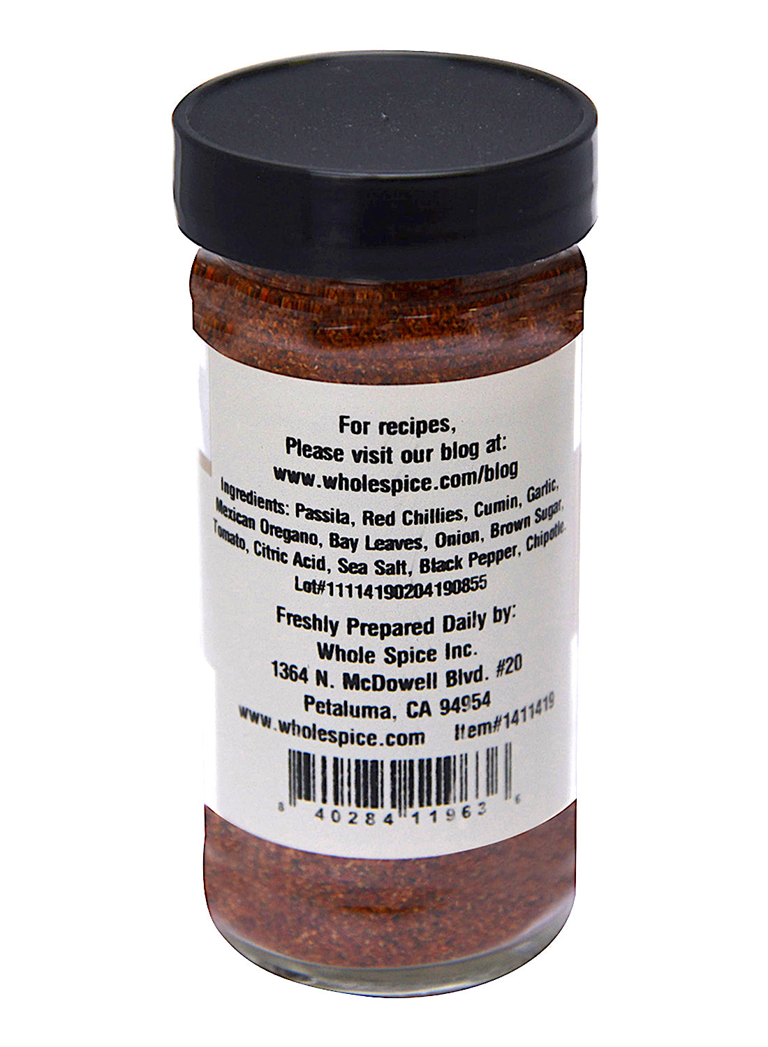A clear spice jar with a black lid from Whole Spice Inc. displays a Taco Seasoning label listing ingredients such as passata, red chilies, cumin, and more, plus preparation tips and a website for additional recipes.