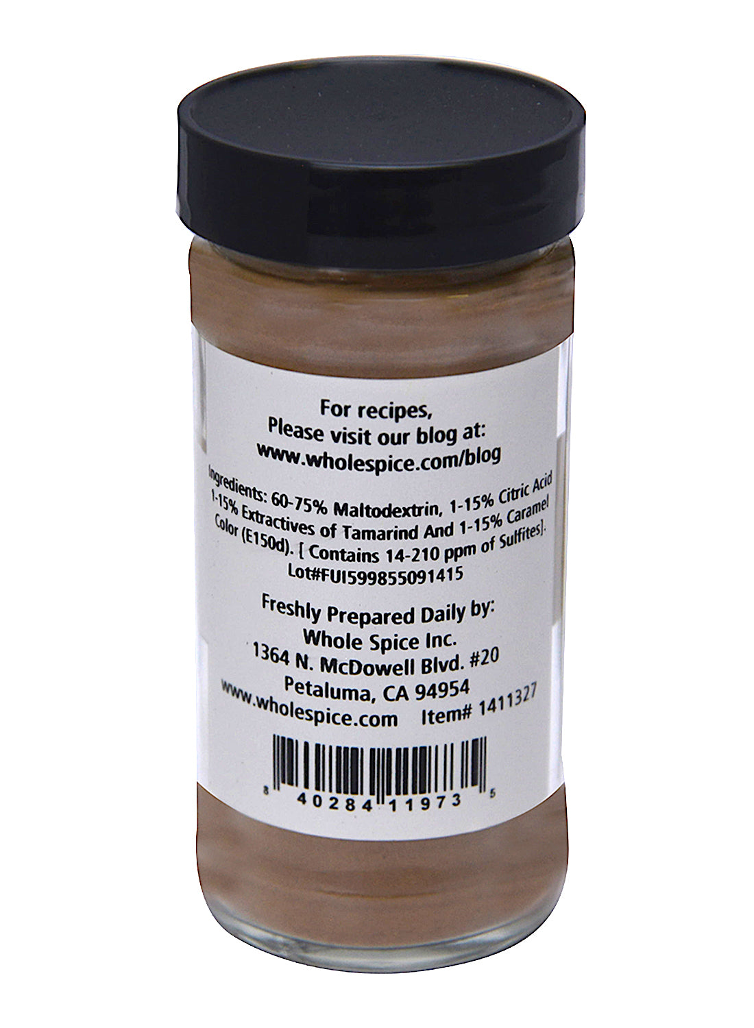 A glass spice jar from Whole Spice Inc. labeled "Tamarind Instant" features a black lid and white label with ingredients, contact info, website for recipes, and a barcode. The jar contains tamarind powder, essential in Southeast Asian dishes.