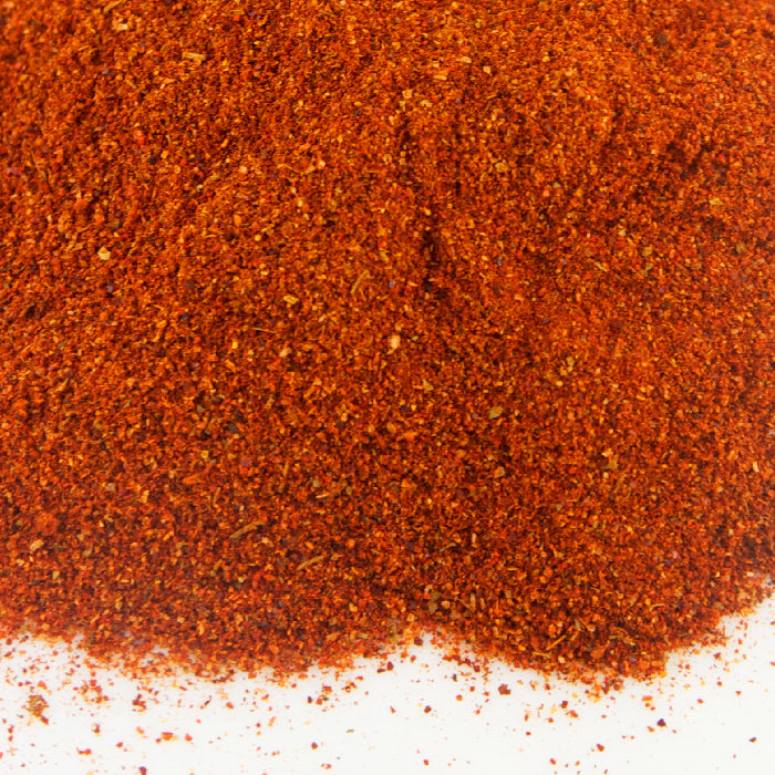 A close-up of Whole Spice Inc. Tandoori Spice Rub, featuring a vibrant pile of finely ground Indian seasoning on a white surface.