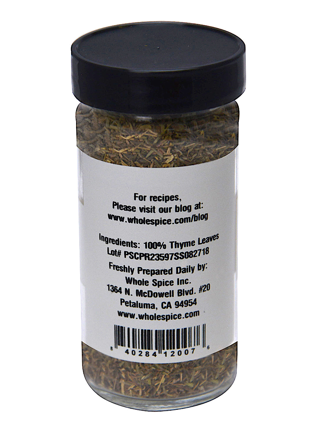 A clear spice jar with a black lid from Whole Spice Inc. contains 100% Thyme Leaves, a versatile kitchen herb. The label shows product info, lot number, company details, website, and barcode.