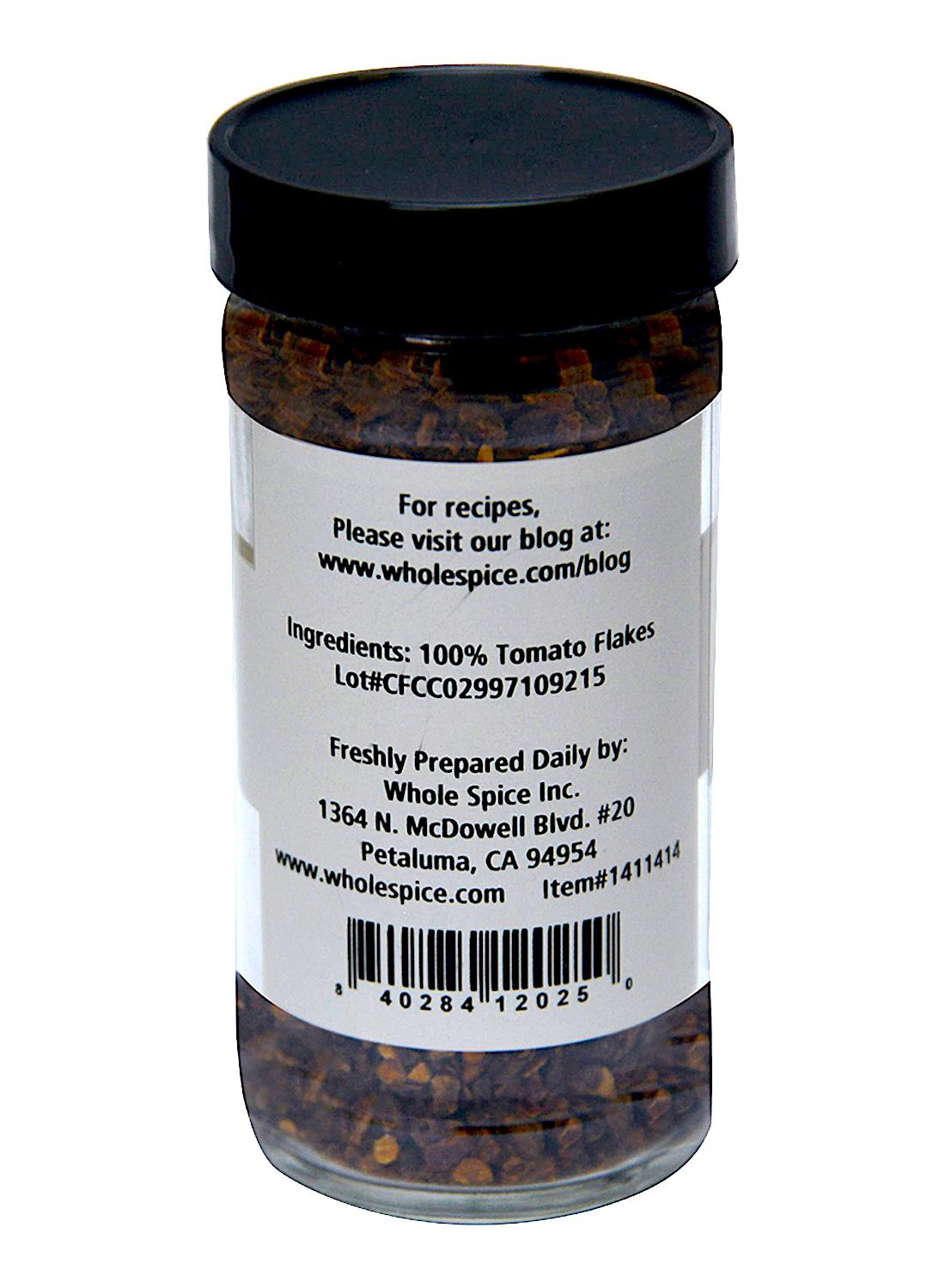 Whole Spice Inc. Tomato Flakes: a clear spice jar with black lid, filled with 100% dehydrated, sulfur dioxide-free tomatoes. Back label includes ingredients and Whole Spice Inc.’s company/contact info.