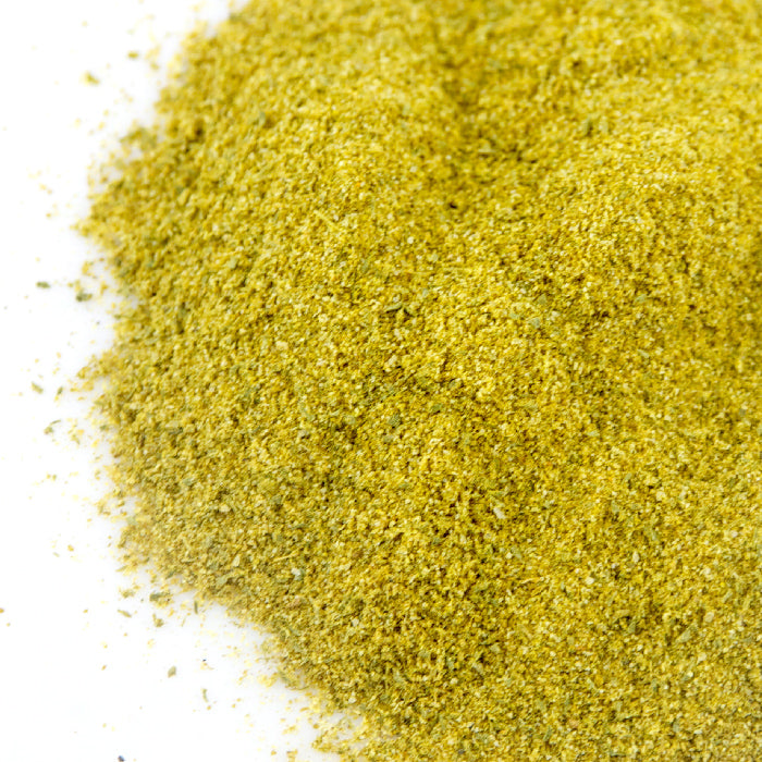 A close-up of Whole Spice Inc. Turkish Spice Rub, a finely ground greenish-yellow blend on a white surface—ideal for authentic Turkish dishes or seasoning shish kebab.