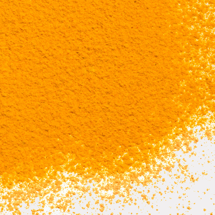 A close-up of vibrant yellow-orange Turmeric Powder Organic by Whole Spice Inc., unevenly scattered across a white surface—dense in the upper left and thinning to the lower right—a classic Indian cuisine ingredient.