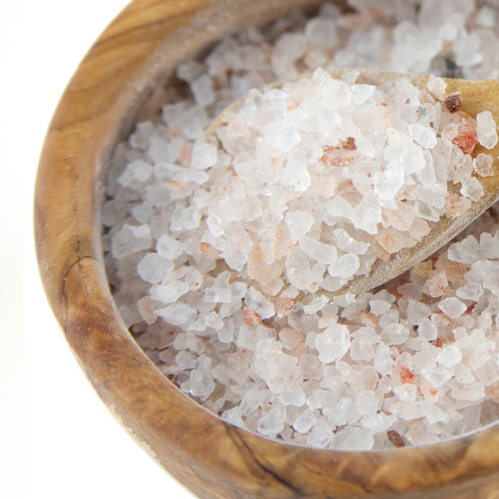 A close-up of Real Utah Salt Coarse by Whole Spice Inc., rich in trace minerals, displayed in a wooden bowl with a wooden spoon scooping up the natural salt crystals.