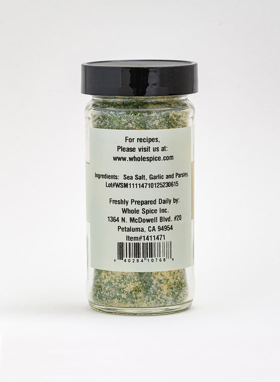 A clear spice jar with a black lid holds Garlic & Parsley Sea Salt by Whole Spice Inc., featuring sea salt, garlic, and parsley—ideal for seasoning dishes or as a gourmet dipping oil. Label includes company and contact details.
