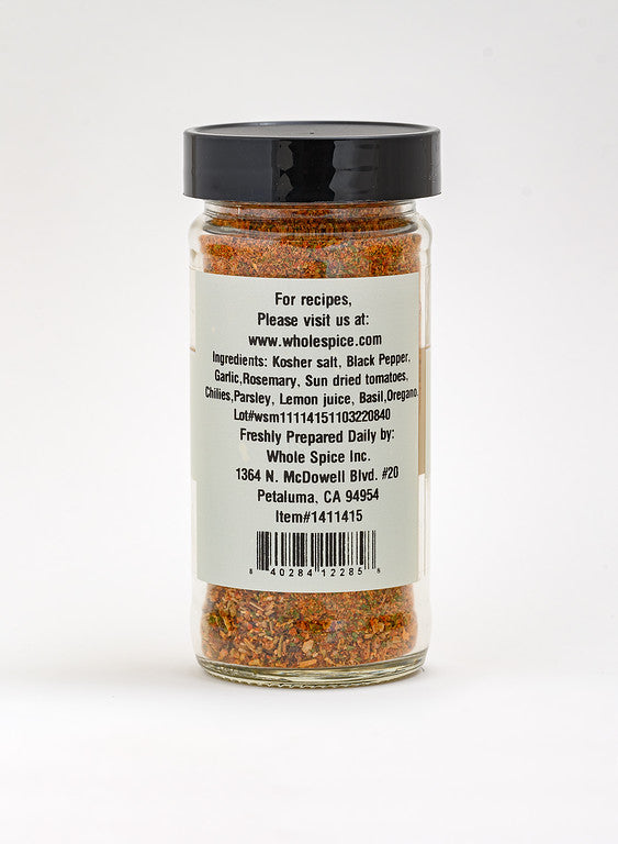 A clear spice jar from Whole Spice Inc. holds Mediterranean Roasting Rub, featuring colorful red, green, and yellow flecks. The black lid tops a label displaying ingredients and contact details—ideal for roasting seasoning blends.