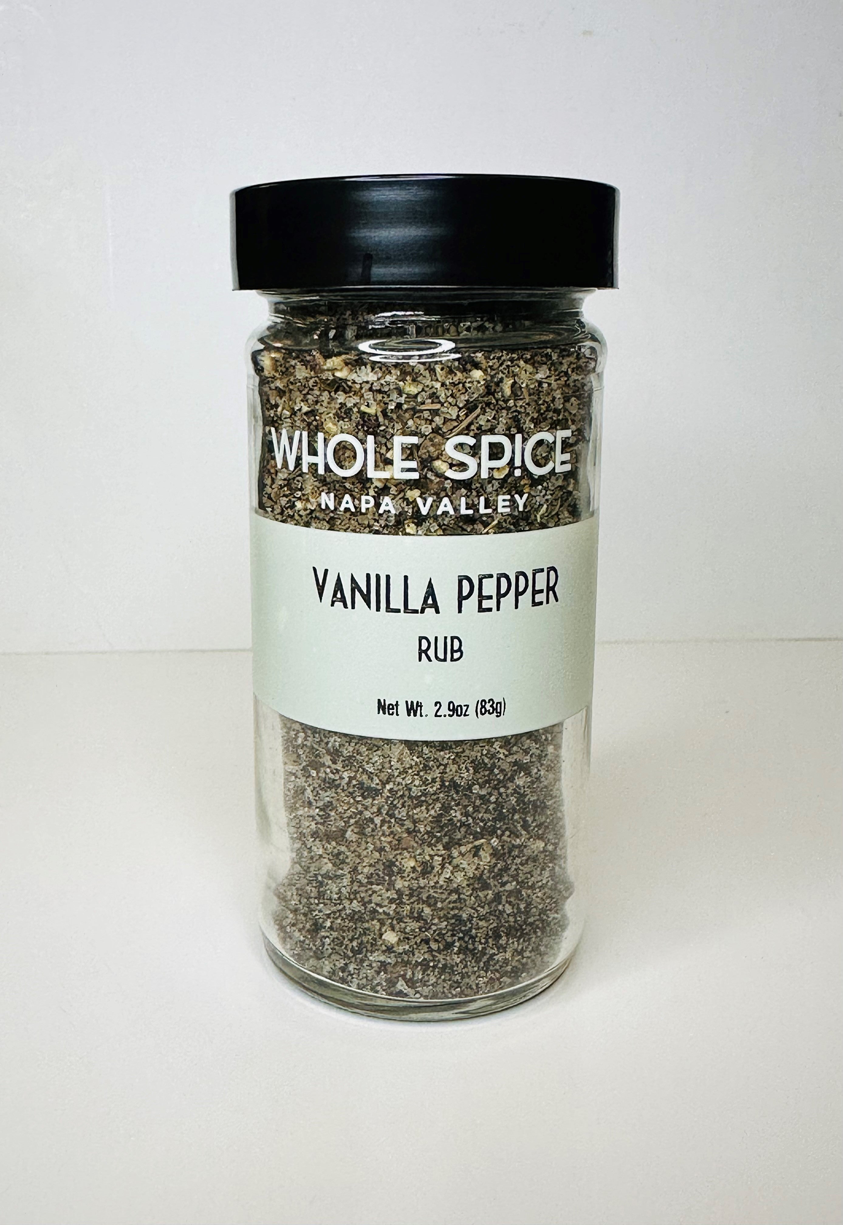A clear glass jar with a black lid contains Whole Spice Inc. Vanilla Pepper Rub gourmet seasoning, Net Wt. 2.9oz (83g), ideal as a flavorful meat rub, displayed on a plain white background.