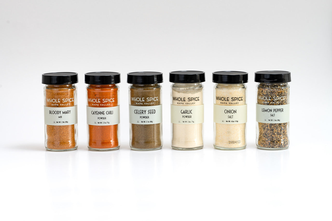 A row of small glass jars from the Whole Spice Bloody Mary Gift Set by Whole Spice Inc., each filled with different spices.