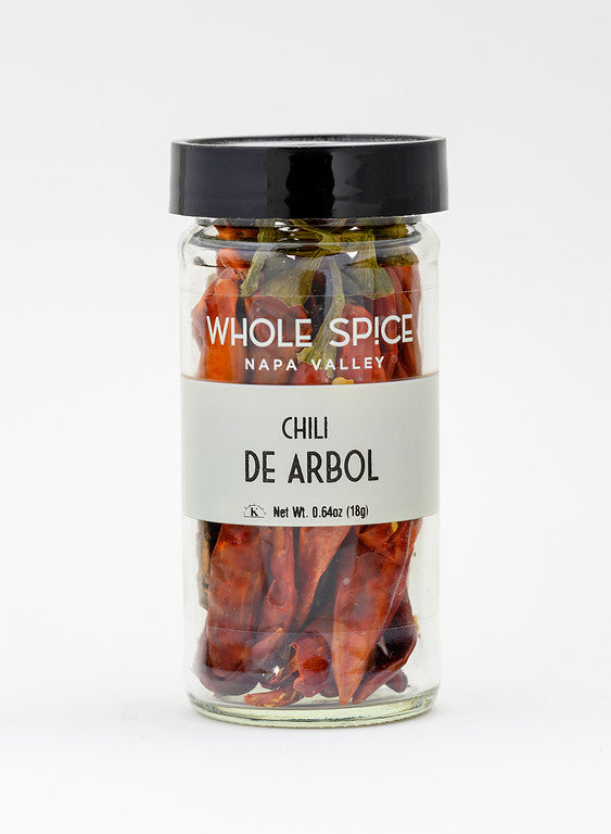 A clear glass jar with a black lid, labeled Whole Spice Inc. Chili De Arbol Whole, holds dried Mexican chili peppers ideal for spicy salsa. The jar displays a net weight of 0.64oz (18g).