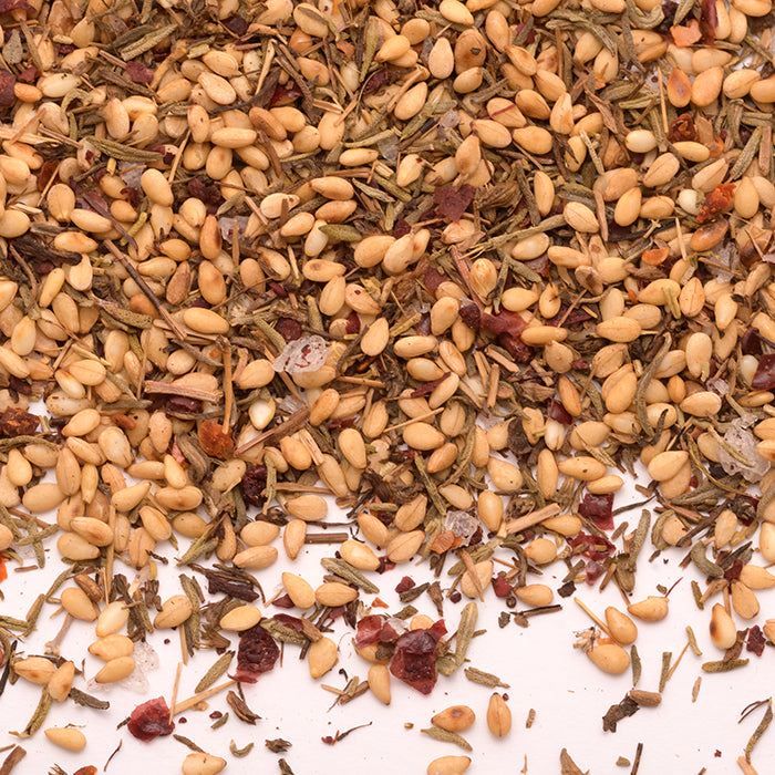 A close-up of Mediterranean Breakfast Seasoning by Whole Spice Inc. shows a blend of toasted sesame seeds, dried thyme, sumac, and aromatic spices on a white surface.