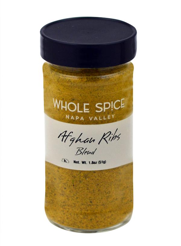A glass jar with a black lid contains yellow grilling spice labeled “Whole Spice Inc. Afghan Ribs Blend, Net Wt. 1.8oz (51g).”.