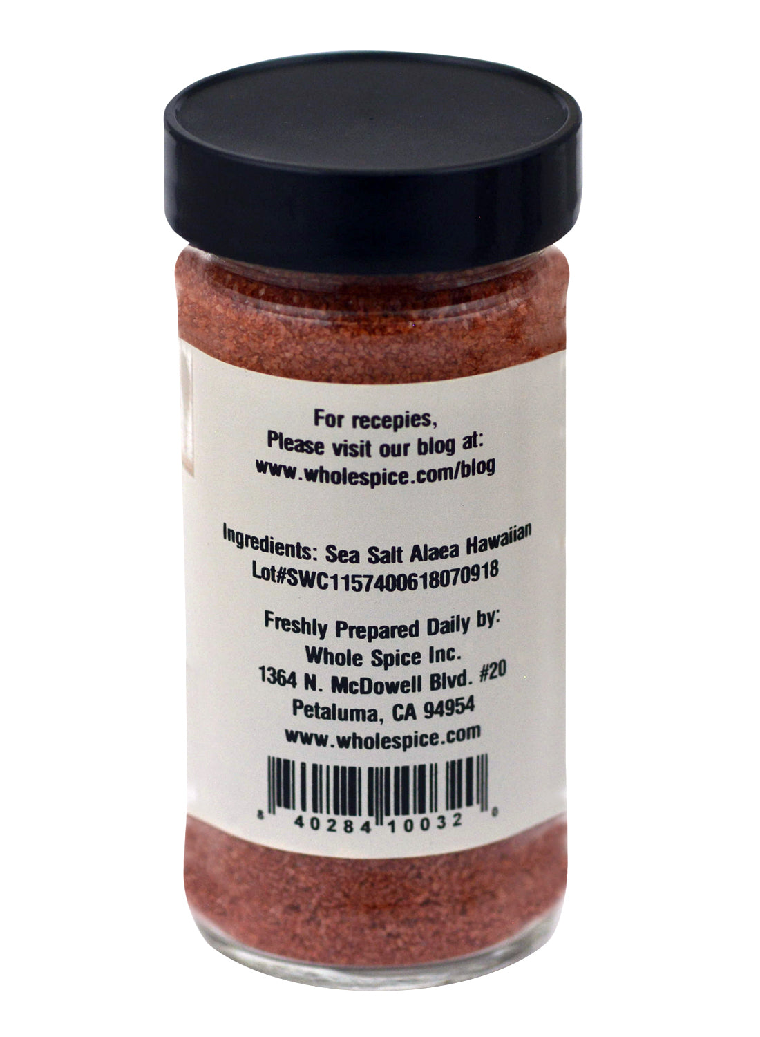 A clear glass jar with a black lid holds Whole Spice Inc. Alaea Hawaiian Sea Salt. The label lists ingredients as Alaea Hawaiian sea salt and includes the manufacturer's details plus website for recipes and info.
