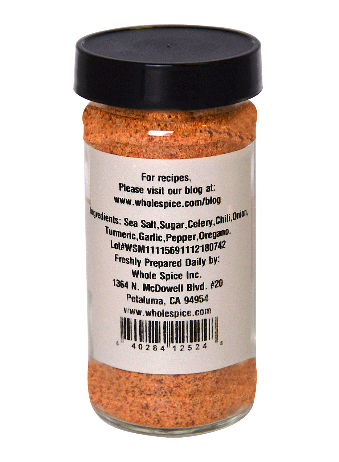 A spice jar with a black lid from Whole Spice Inc. displays a label listing gourmet salt, sugar, celery, chili, onion, turmeric, garlic, pepper, and oregano—ingredients in their All Purpose Salt Seasoning.