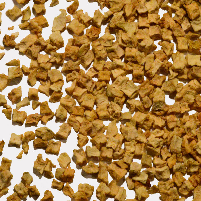 Whole Spice Inc. Apple Dices are small, light brown, irregular pieces with a rough, slightly crumbly texture scattered on a white surface, highlighting their unsulfured, dehydrated quality.