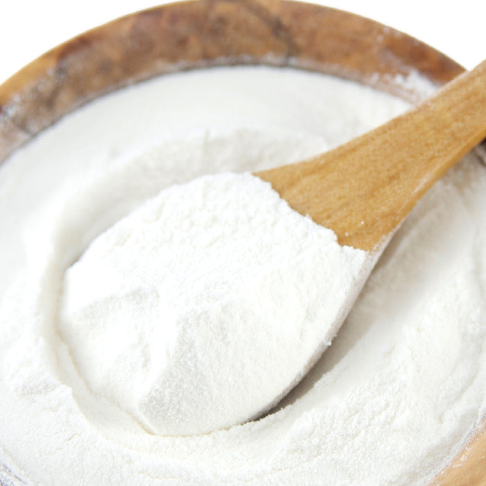 A wooden spoon scoops Apple Cider Vinegar Powder from a wooden bowl filled with the powder by Whole Spice Inc.