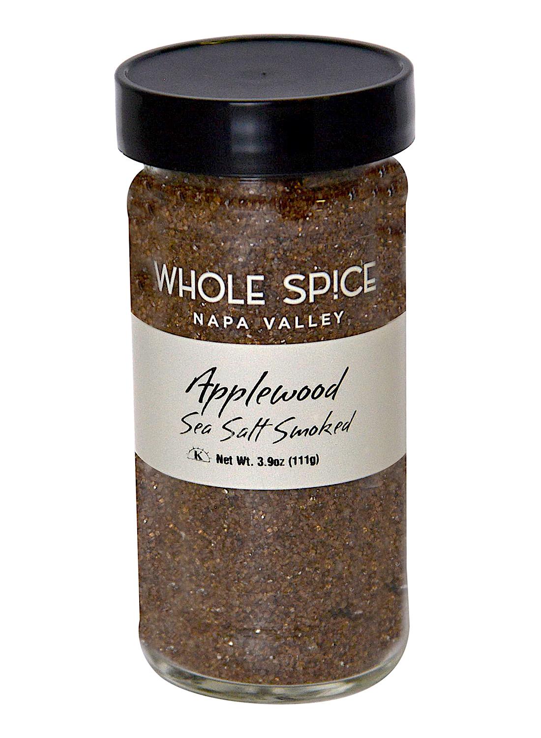 A 3.9 oz (111 g) glass jar of Whole Spice Inc. Applewood Smoked Sea Salt with a black lid and labeled with the product name; this natural, dark, coarse sea salt delivers a rich smoky applewood flavor and aroma.