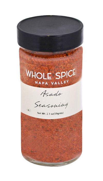 A clear glass jar with a black lid is filled with red Asado Seasoning by Whole Spice Inc.—ideal as a rub for roasted chicken. The label states: Asado Seasoning, Whole Spice Inc., Net Wt. 2.1 oz (59g).