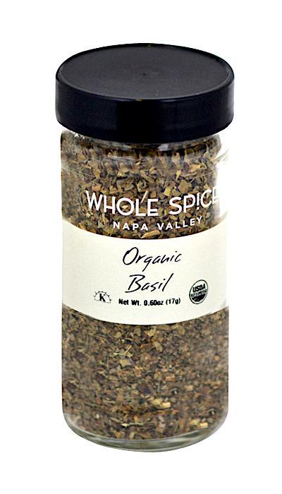 A clear glass jar of Whole Spice Inc. Basil Organic with a black lid features a white label displaying the brand, product name, net weight, and USDA Organic seal for these fragrant sweet basil leaves.