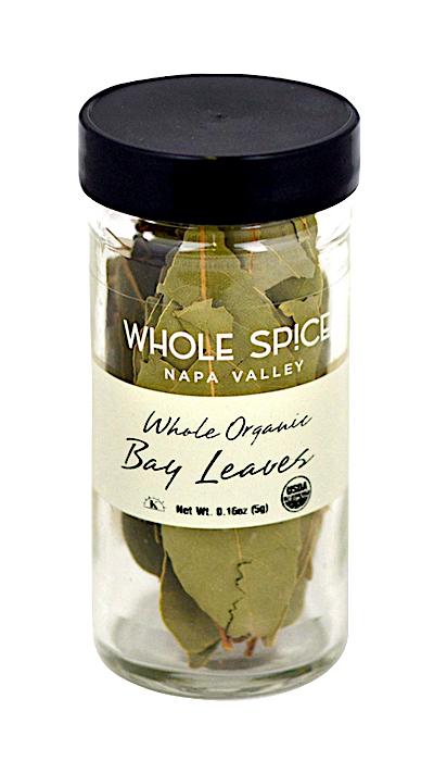 A clear glass jar with a black lid labeled Whole Spice Inc. Bay Leaves Whole Organic contains dried Laurus nobilis leaves.